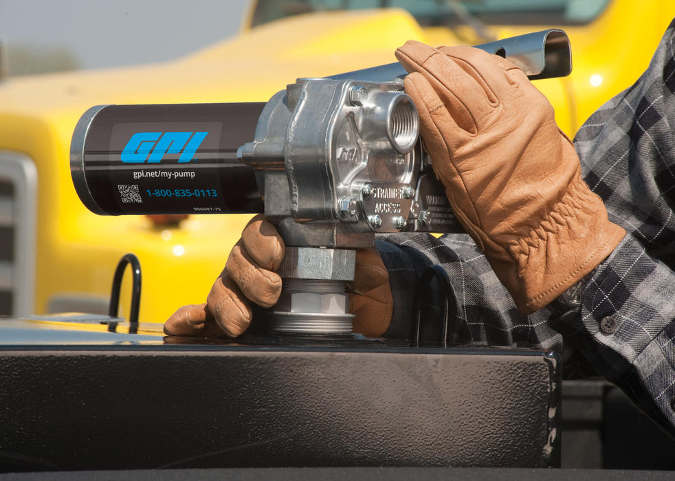 Man attaching GPI M-240 Fuel transfer pump on fuel tank in front of big truck.