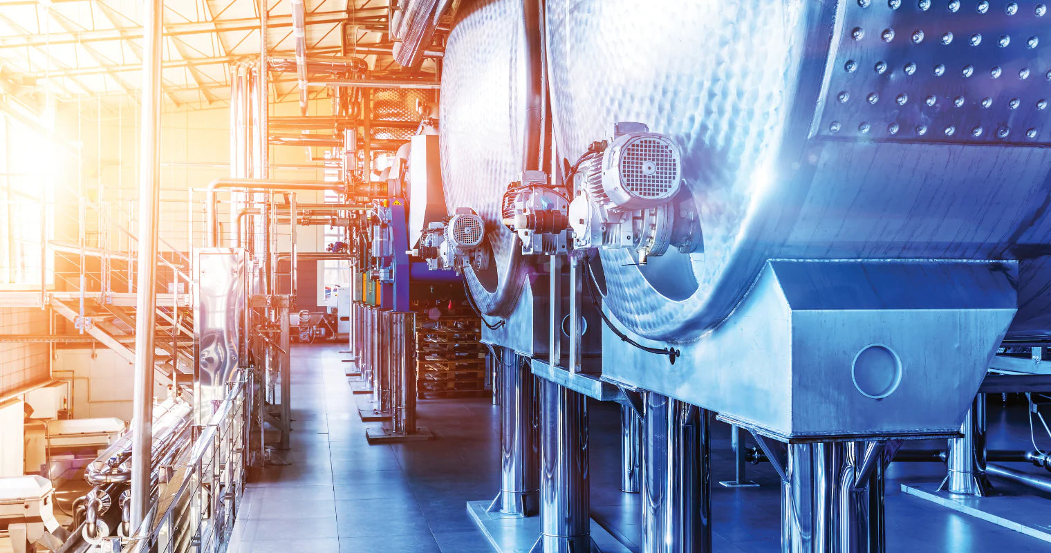 Industrial setting with large metallic tanks and equipment in a factory.