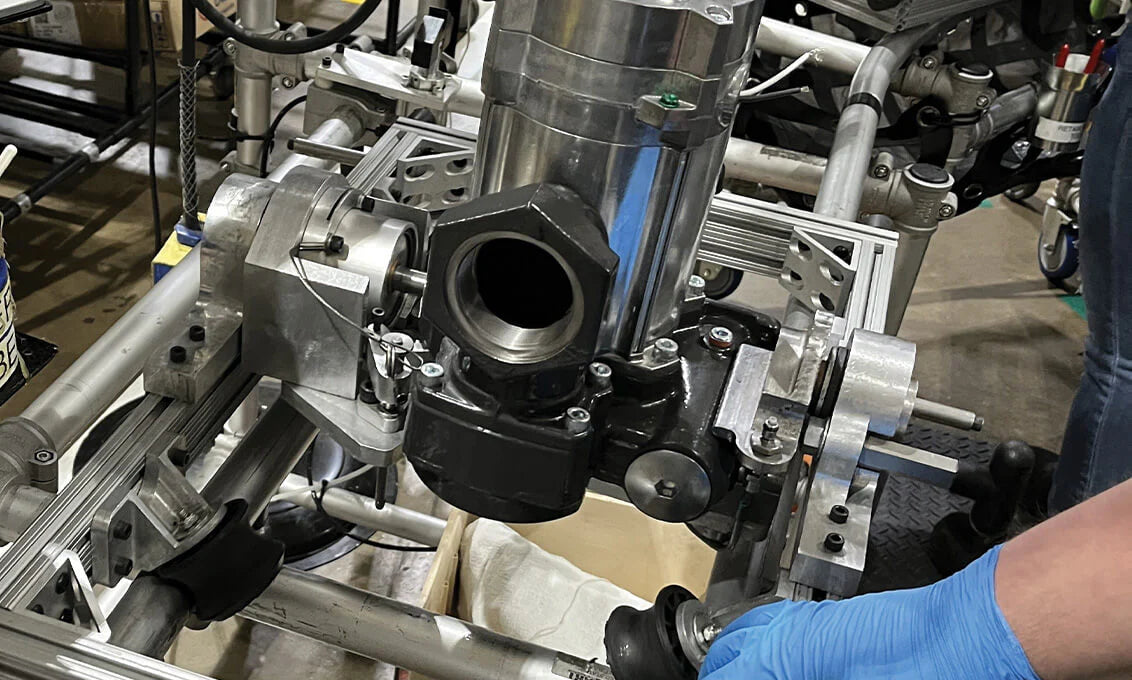 Close-up of a mechanical assembly with a person wearing blue gloves in an industrial setting